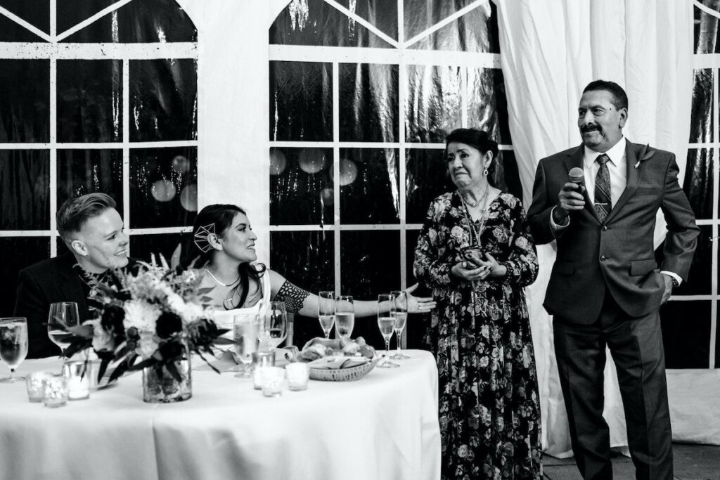 Elegant wedding reception under the white-draped tent at Woodend, with chandeliers, round tables, and natural light