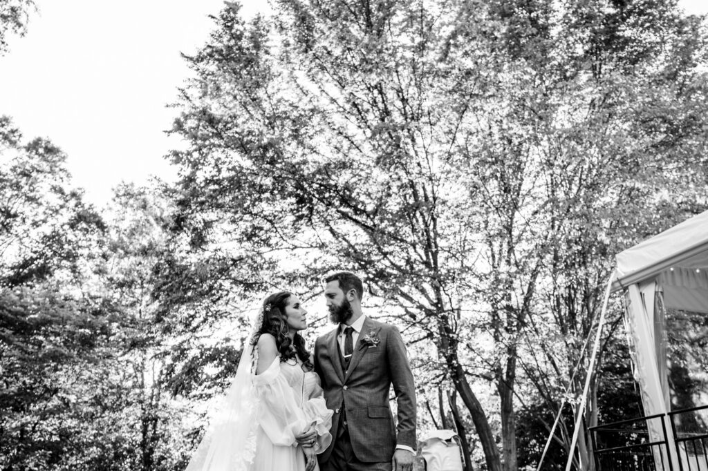 Bride and groom walking through forest path at Woodend Sanctuary, surrounded by fall foliage and soft golden light