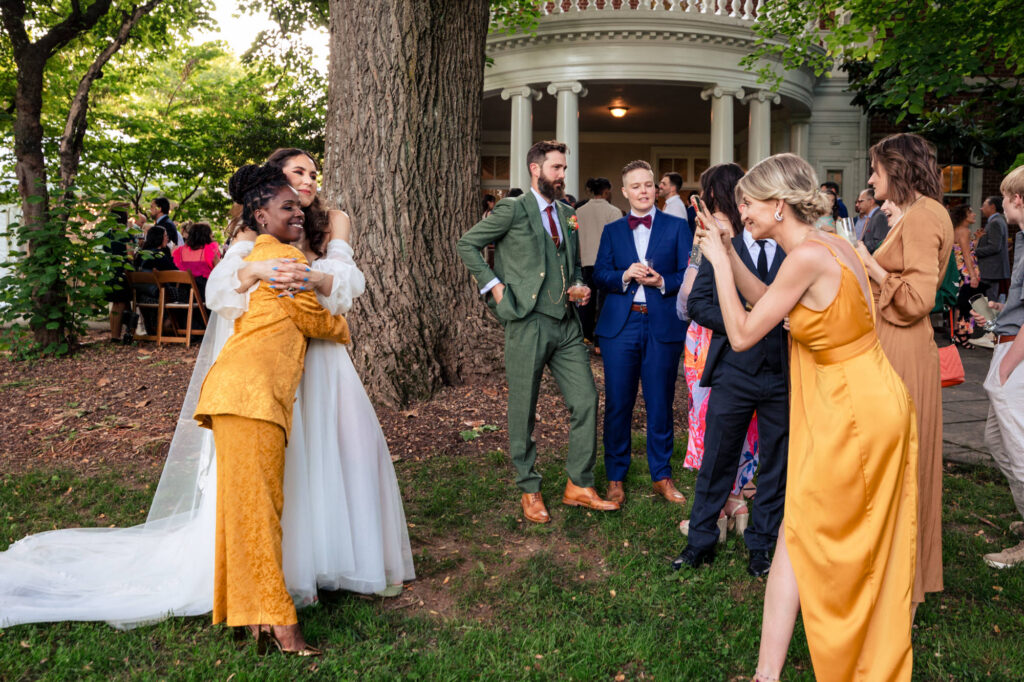 Guests mingling during cocktail hour on the lawn outside the mansion at Woodend, with string lights and forest backdrop