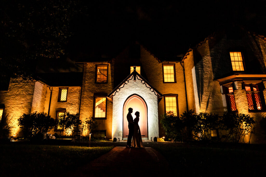 Night portrait of a couple in front of the glowing facade of President Lincoln’s Cottage