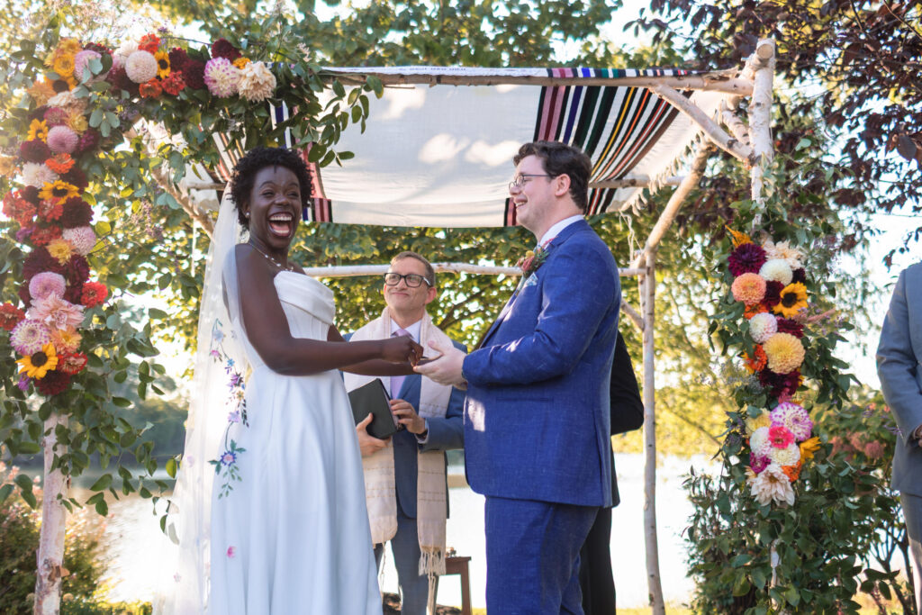 Nia and Oliver holding hands during their backyard ceremony under the chuppah in Maryland.